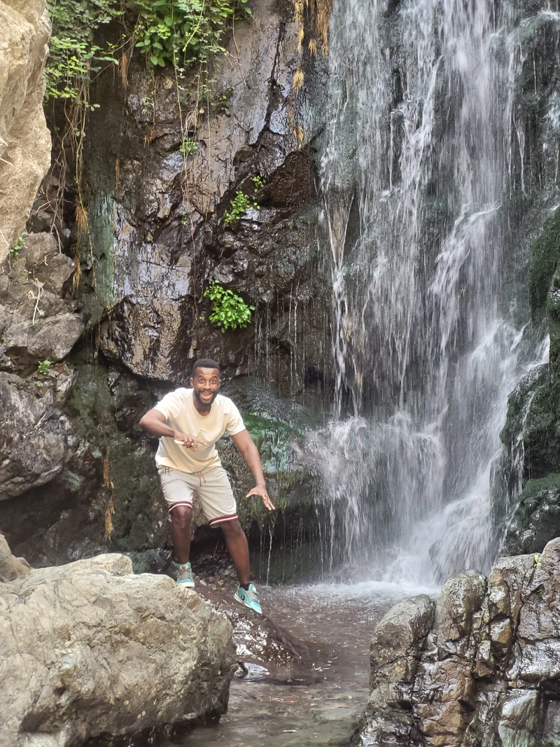 Al-Fahami Toihir in front of a waterfall